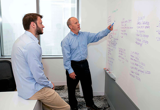 Two coworkers working on white board brainstorming session